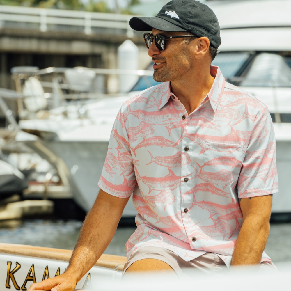 Man sitting on boat wearing Tommy gamefishing button-up shirt with marlin dolphin fish and wahoo print