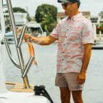 Man rigging fishing lure wearing Tommy custom fishing shirt with marlin and dolphin fish pattern